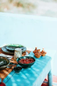 A traditional Moroccan table set with a bowl of tomato-based salad, ceramic dishes, and small tagine spice holders, representing Moroccan cuisine